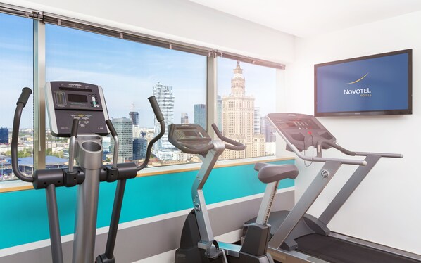 A gym with exercise equipment and a city view. - Novotel Warszawa Centrum (Warsaw)