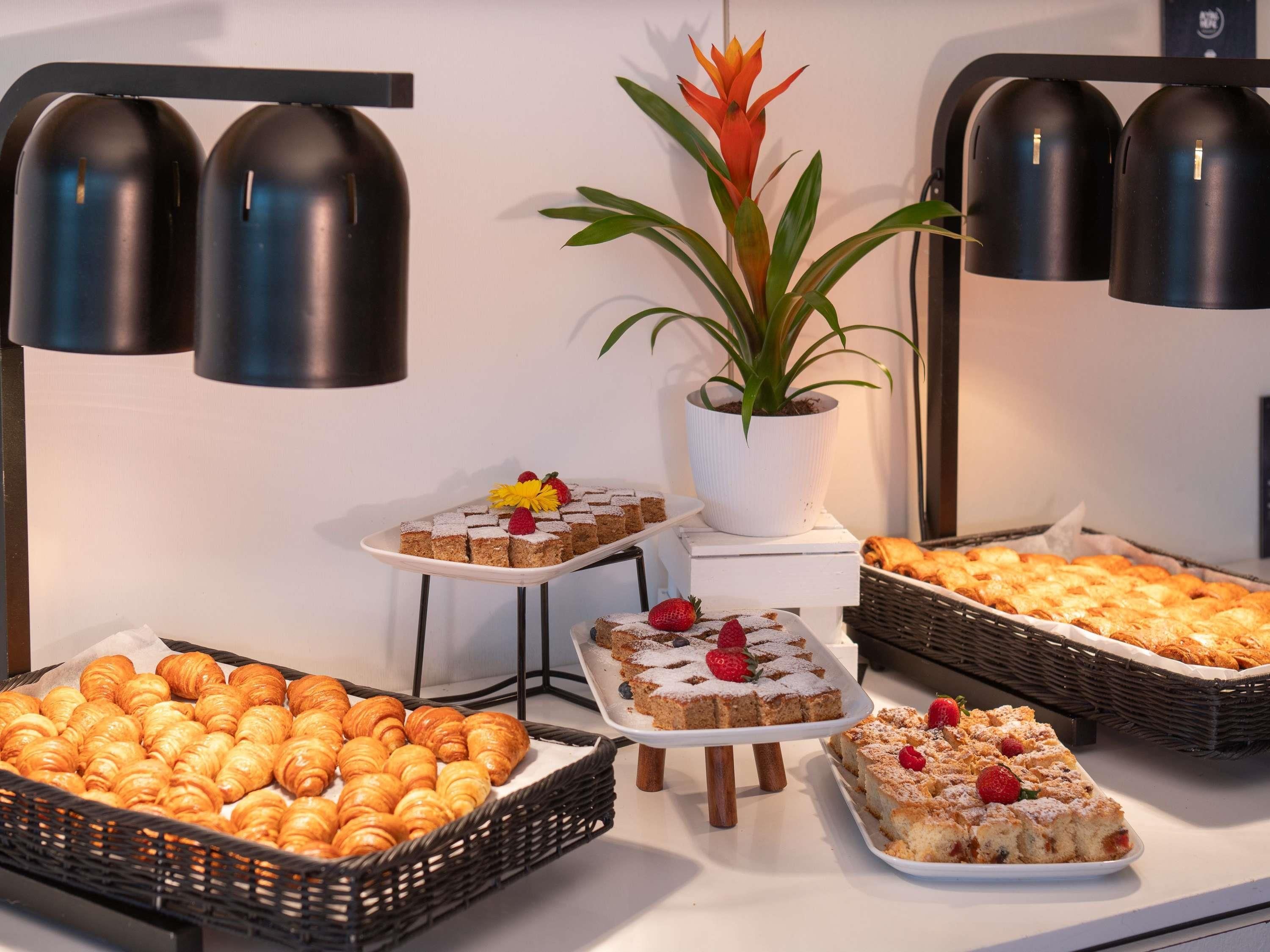 Una mesa de buffet con diversas opciones de repostería, incluyendo pasteles, tartas y postres.
