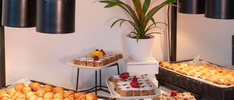 Una mesa de buffet con diversas opciones de repostería, incluyendo pasteles, tartas y postres.