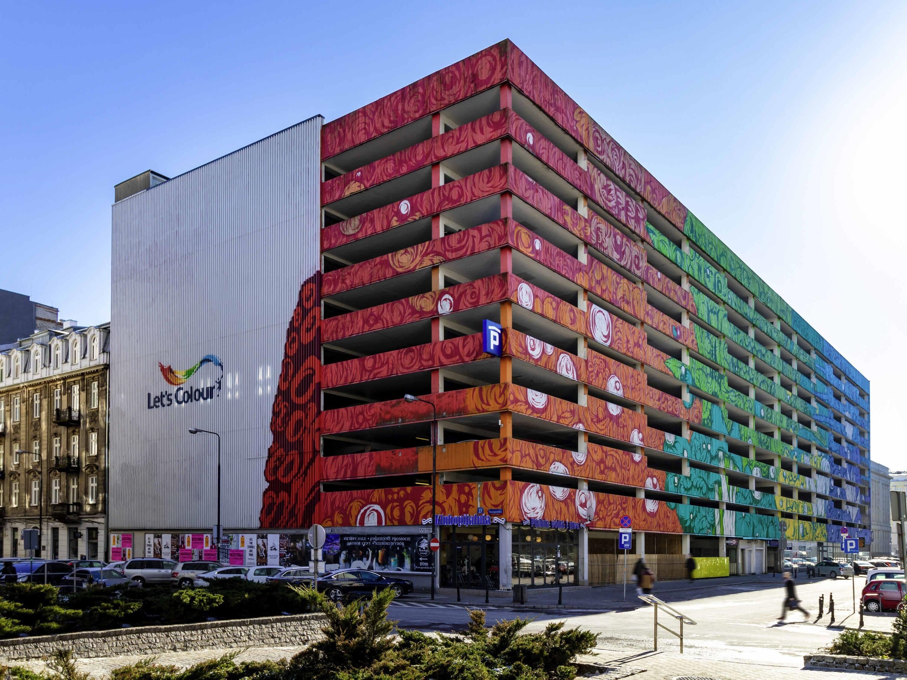 Un parcheggio multipiano con pareti esterne dai colori vivaci e motivi decorativi, e un grande annuncio pubblicitario su un lato.