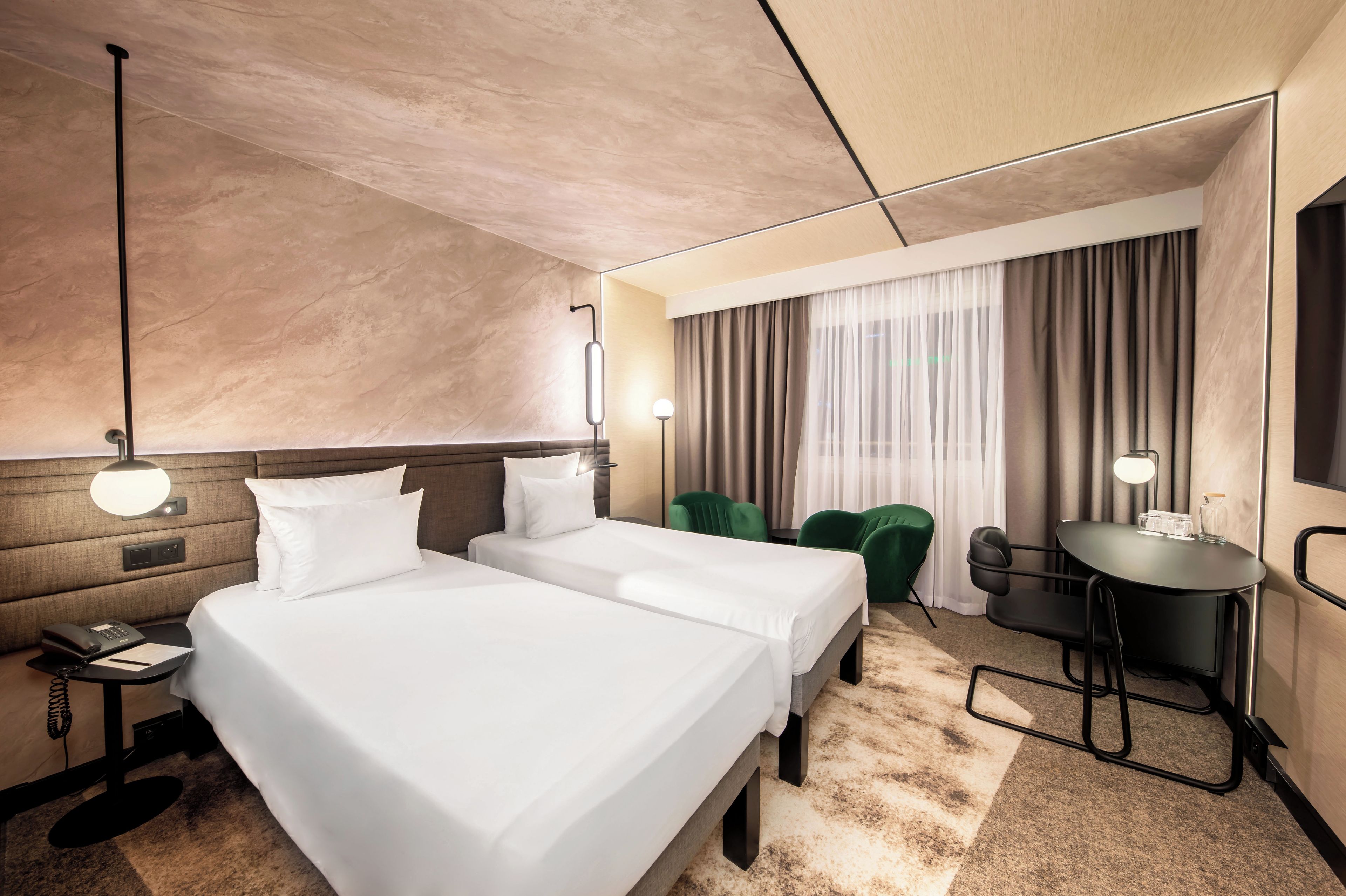 Habitación de hotel con dos camas, un escritorio, una silla, un teléfono y una lámpara.