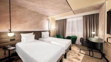 Habitación de hotel con dos camas, un escritorio, una silla, un teléfono y una lámpara.