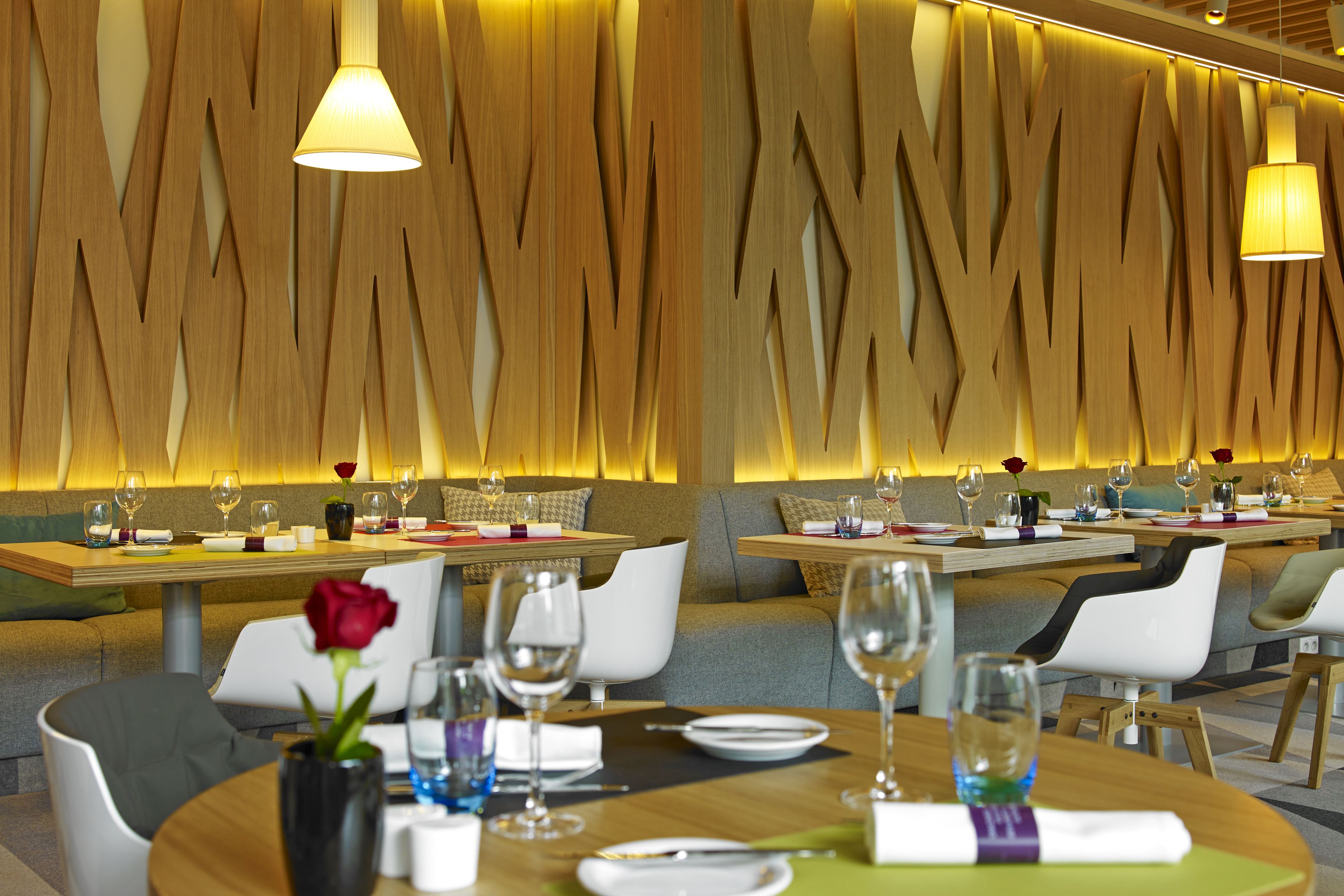 A restaurant with wooden wall decor, round tables, and white chairs.