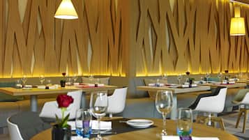 A restaurant with wooden wall decor, round tables, and white chairs.
