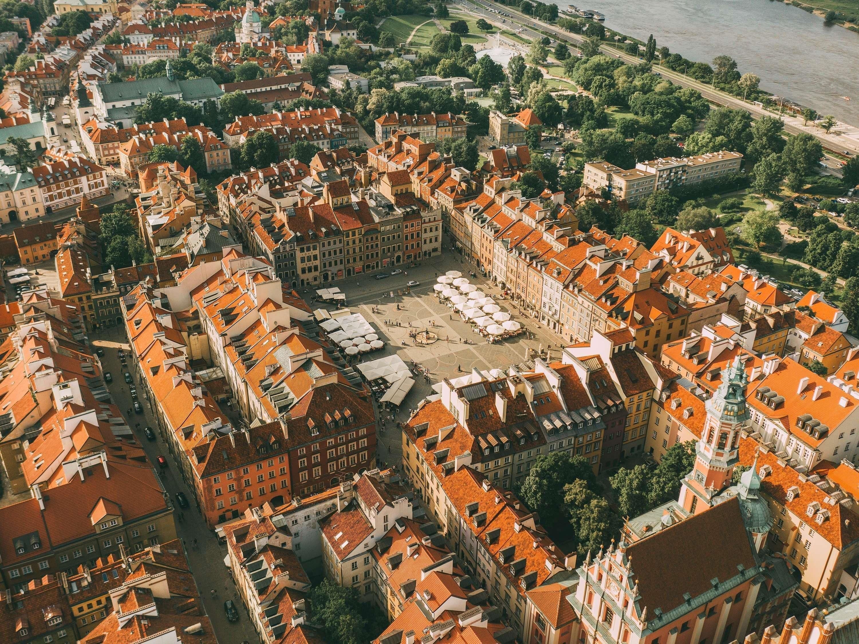 Luchtbeeld van een historische stad met rode dakpannen, een centraal gelegen plein en een rivier.