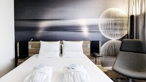 A modern hotel room with a large bed, two white towels, a desk with a lamp, and a view of the sea. - Novotel Warszawa Centrum (Warsaw)