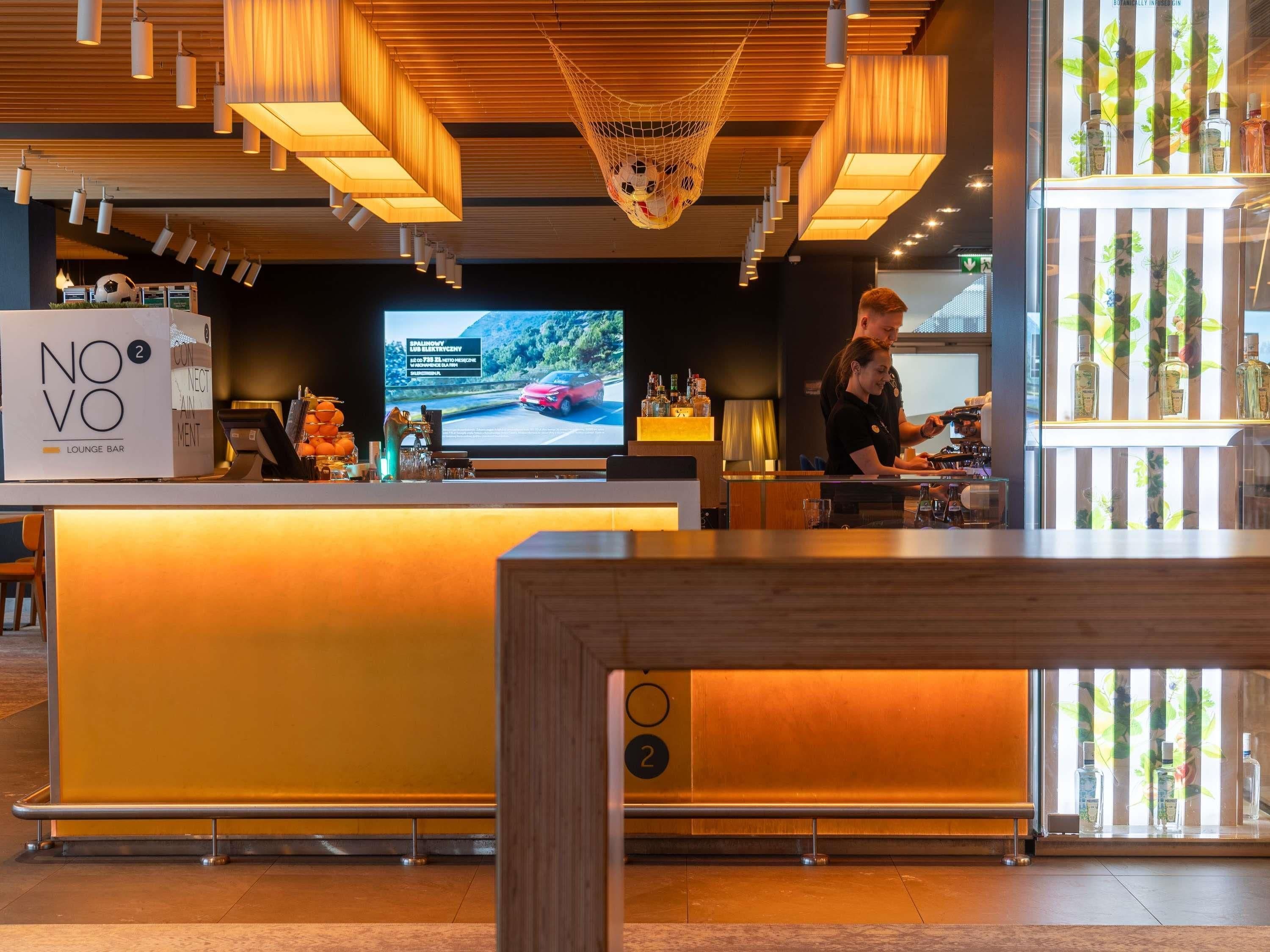 Un moderno bar lounge con techo de madera, una pantalla de televisión y una barra.