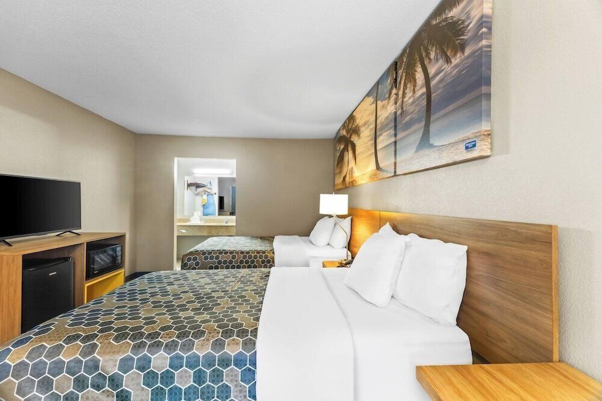 A hotel room with a large bed, a television, a desk, and a bathroom visible through an open door.