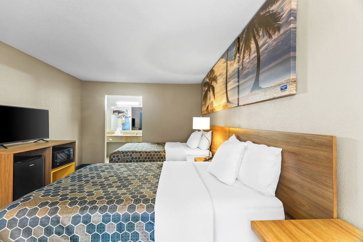 A hotel room with a bed, a TV, a desk, and a microwave.