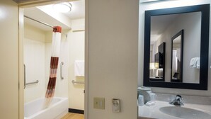 Une salle de bain avec une baignoire, un rideau de douche, un lavabo et un miroir.