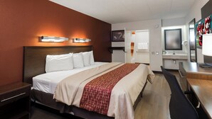 Une chambre d’hôtel comprenant un lit, une table de chevet et un bureau avec une chaise.