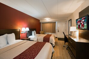 Een hotelkamer met twee bedden, een televisie, een bureau en een stoel.