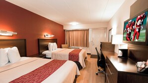 Une chambre d’hôtel avec deux lits, un bureau, une chaise, une télévision et une fenêtre avec des rideaux.