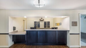 A reception area with a dark blue counter, a white door, and a sign indicating amenities like pool and spa. - Best Western Capital City Inn (Sacramento)