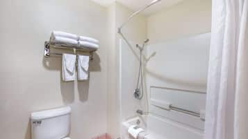 A bathroom with a toilet, a shower with a glass door, and a towel rack with folded towels.