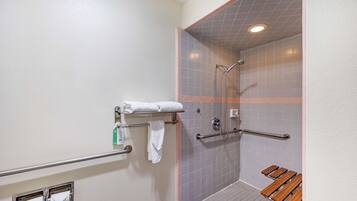A shower area with a grab bar, a towel rack, and a wooden bench.