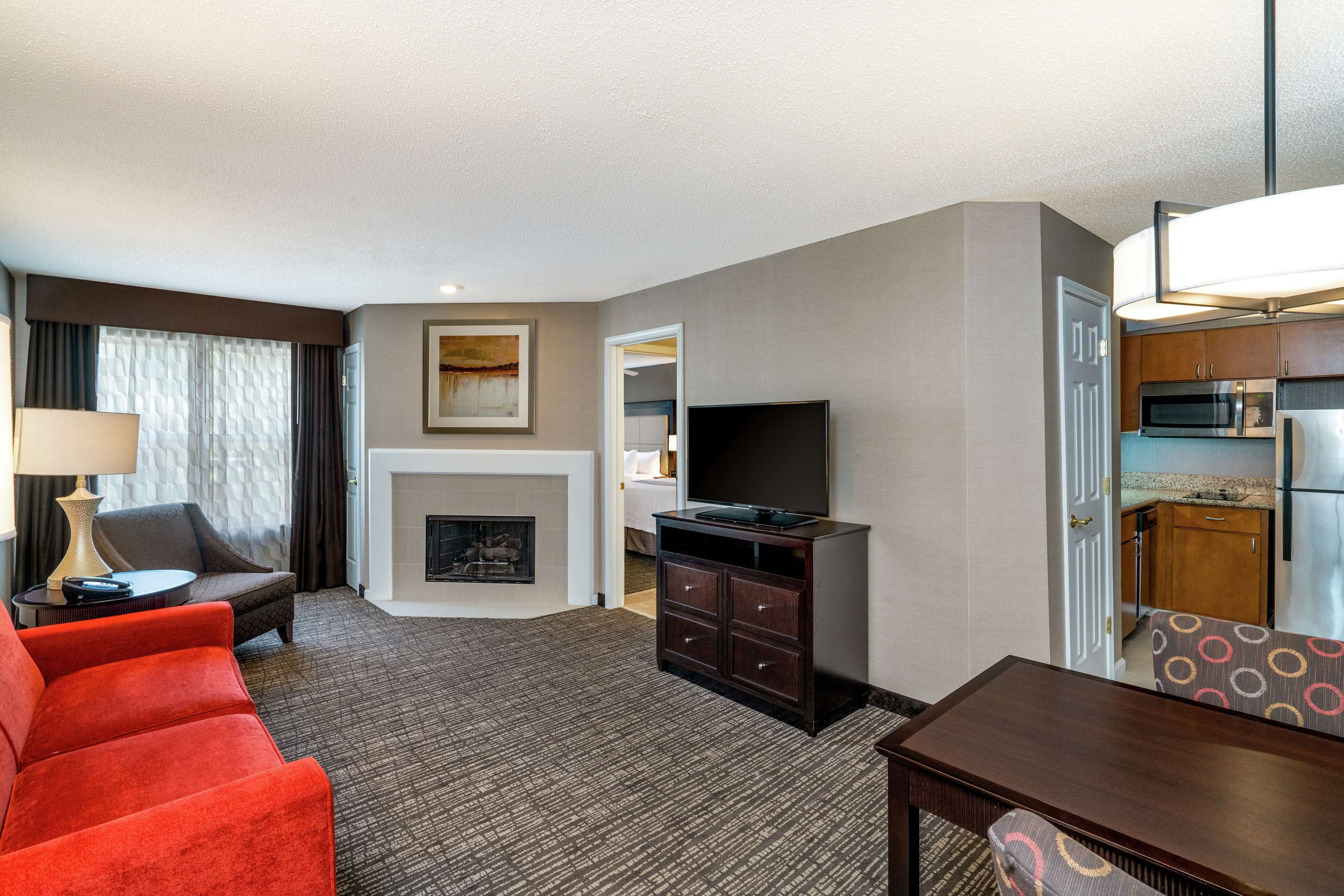 A hotel room with a living area featuring a sofa, a TV, a fireplace, and a dining table.