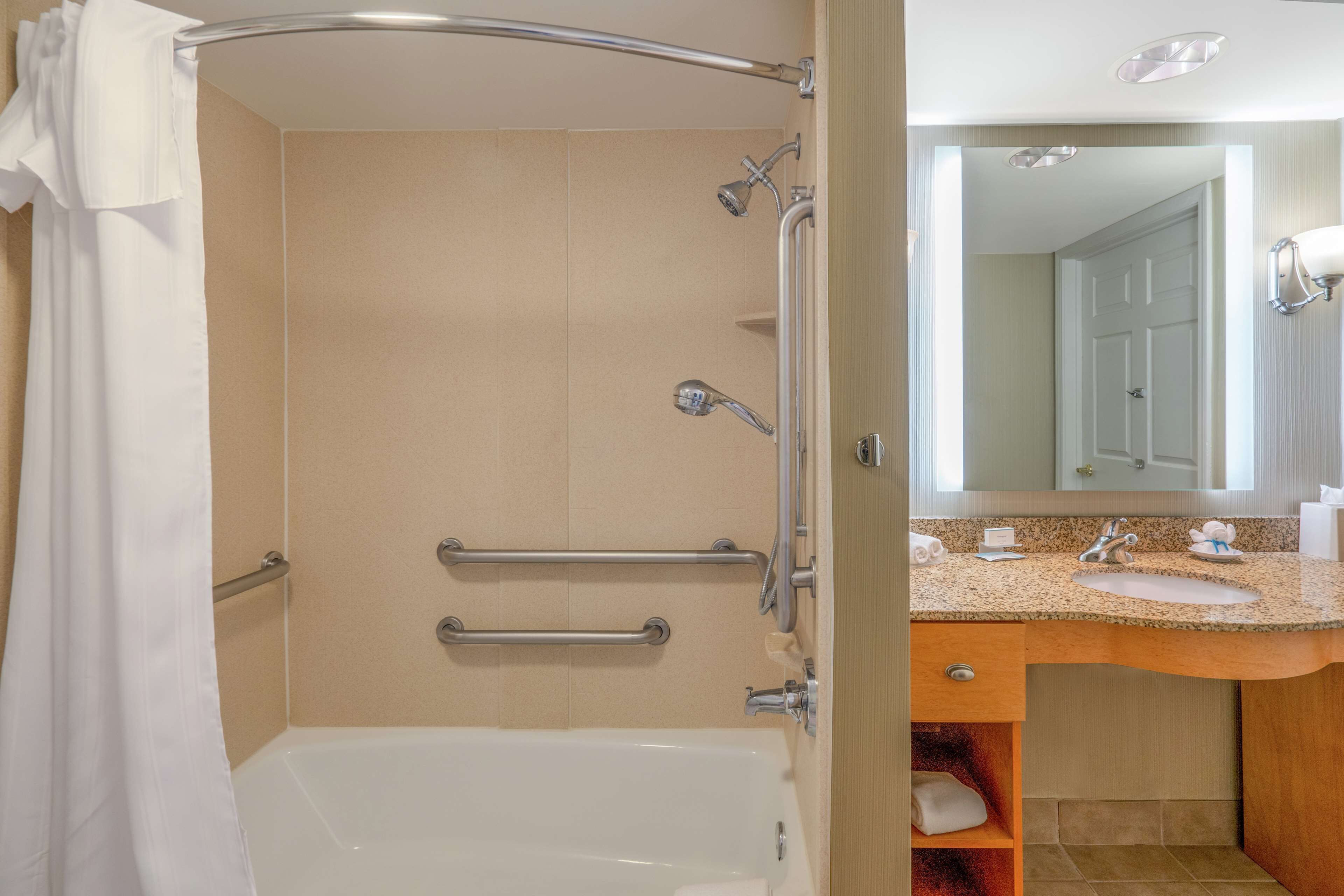 Un baño con bañera, ducha y barras de apoyo.