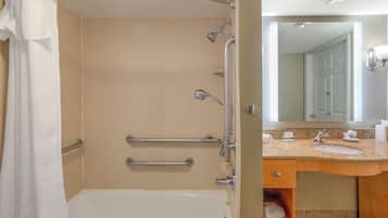 Un baño con bañera, ducha y barras de apoyo.