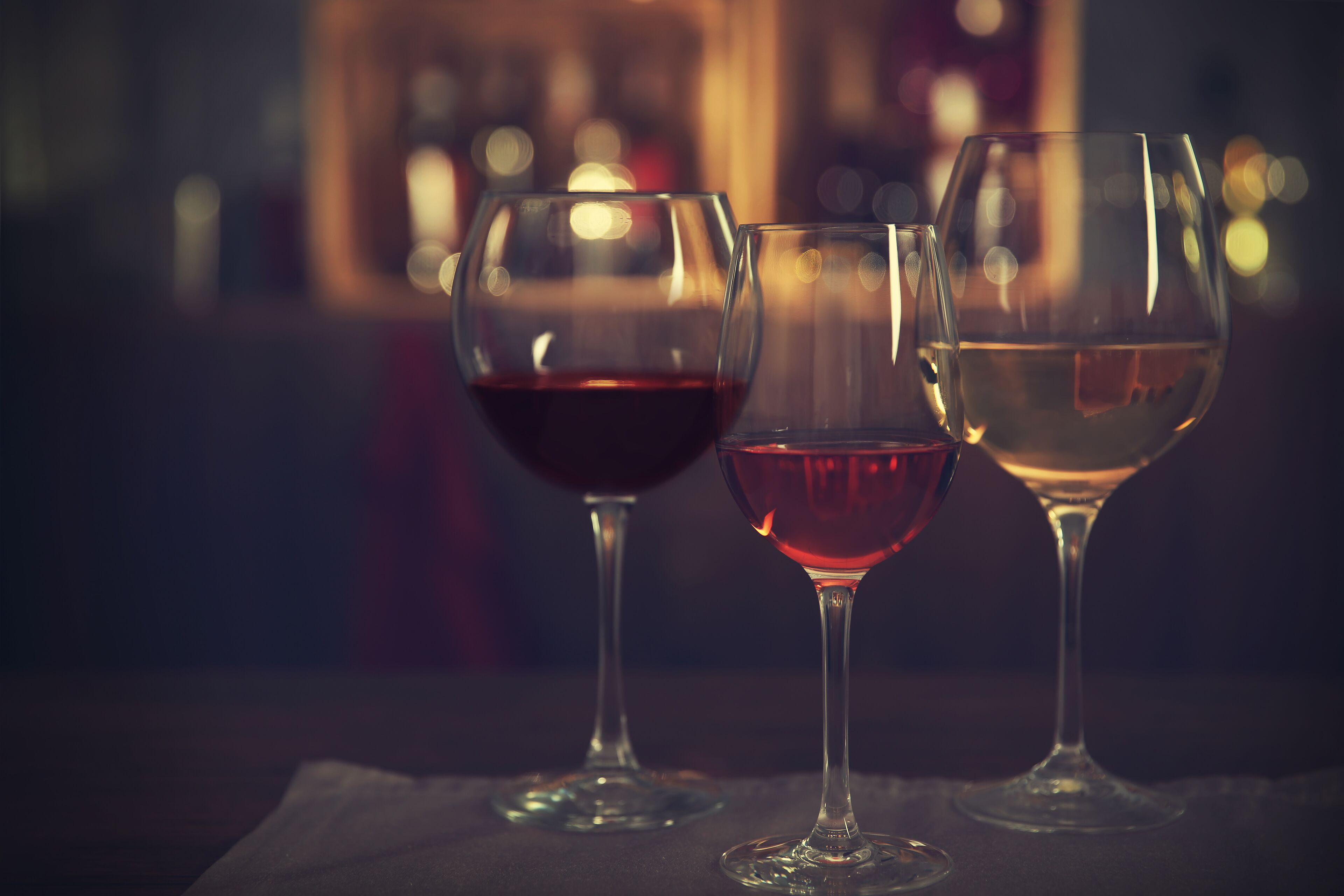 Three wine glasses on a table with a blurred background.