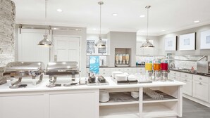 Een moderne keuken met een buffetopstelling, inclusief een koffiehoek, drankdispensers en diverse serveerschaaltjes.