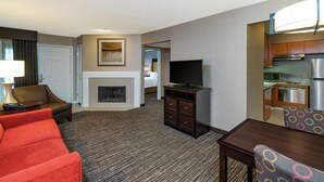 Een hotelkamer met een zithoek, een open haard, een televisie, een eethoek en een kitchenette.