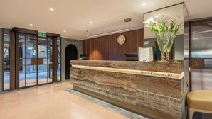 Een hotel receptiebalie met een marmeren aanrecht, een klok en een bloevas.