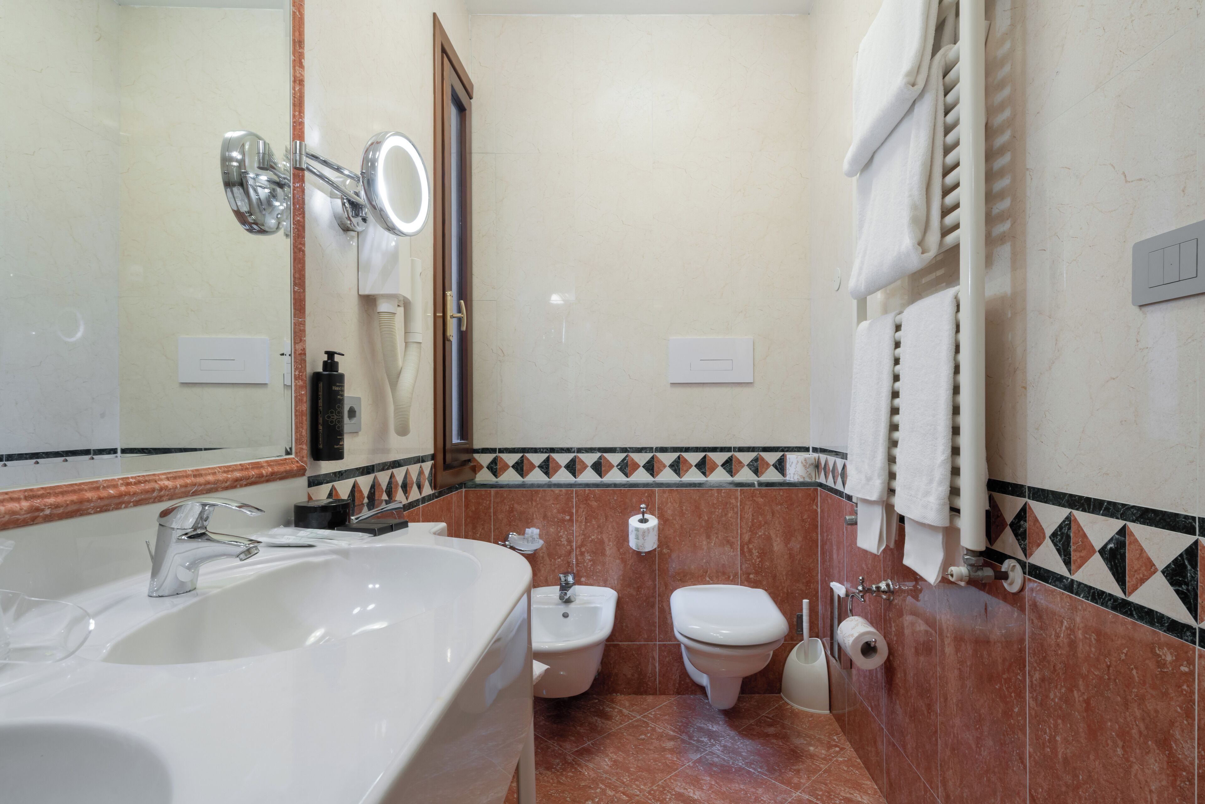 A bathroom with a large sink, a bidet, a toilet, and a mirror.