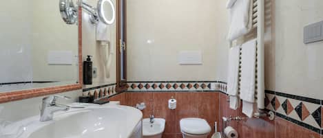 Um banheiro com uma pia grande, um bidê, um vaso sanitário e um espelho.