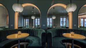 Een modern interieur met groen bekleden zitmeubilair, een ronde tafel en een decoratieve lamp.