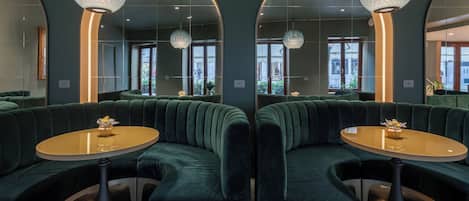 A modern interior with green upholstered seating, a round table, and a decorative light fixture.