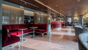Een moderne zithoek met rode zitplaatsen, een bar en een glanzende vloer.
