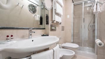 Une salle de bain moderne dotée d’un grand lavabo, de toilettes, d’un bidet et d’une douche à parois de verre.