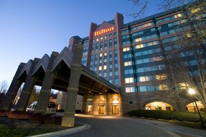 A Hilton hotel with a modern architectural design, featuring a prominent 'Hilton' sign, a covered entrance, and a well-lit facade.