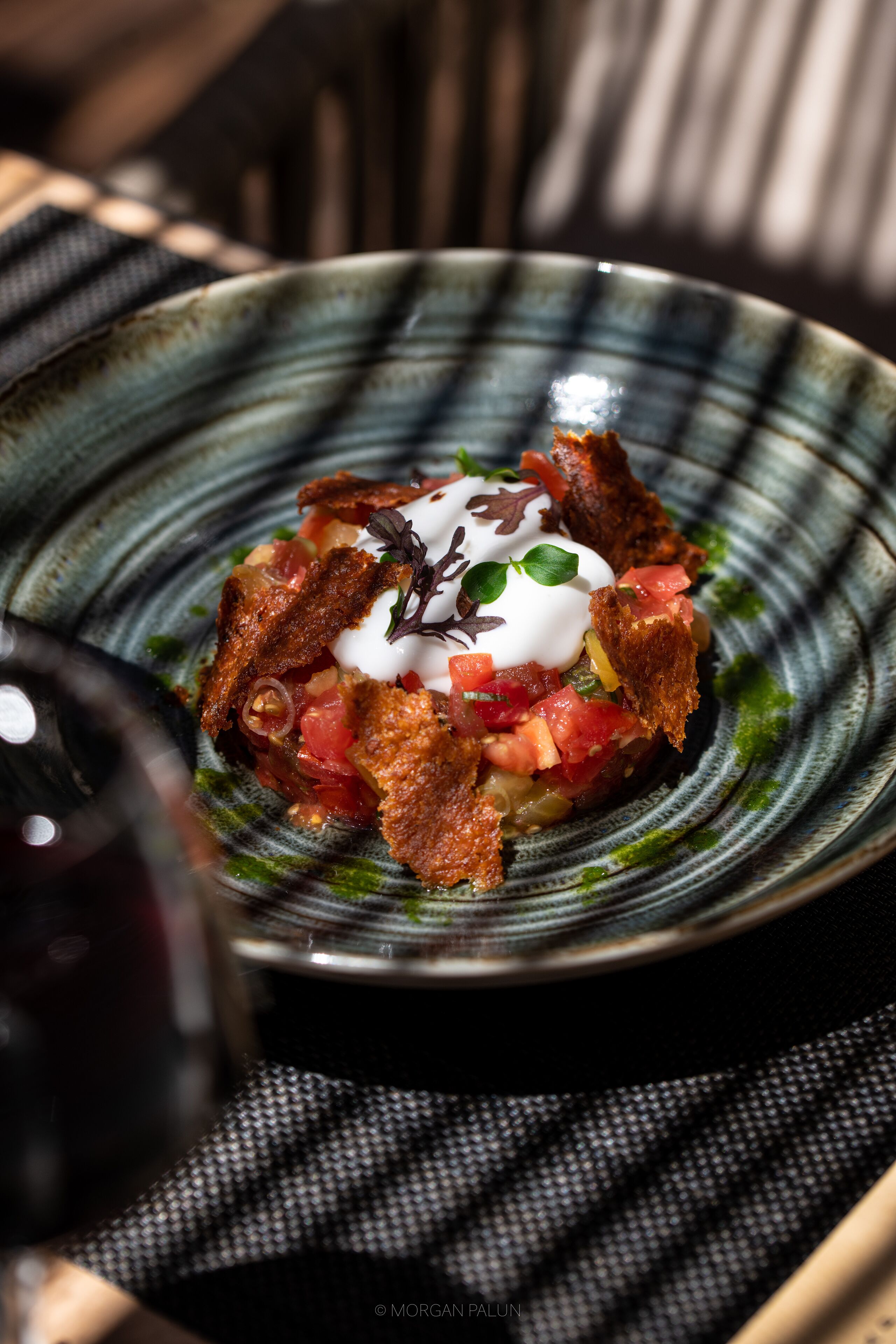A plate of food with a decorative garnish, a bottle of wine, and a checkered napkin.