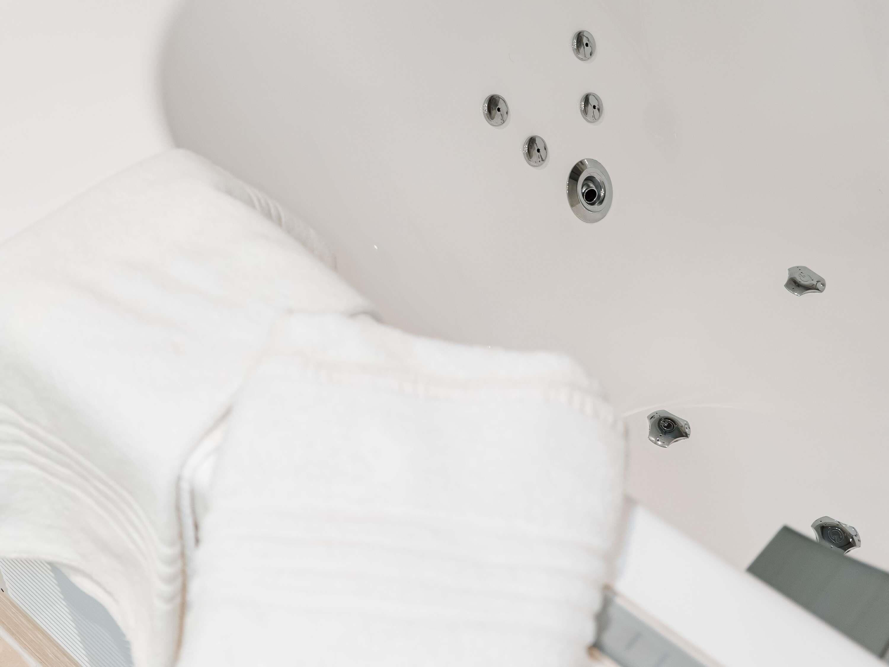 A white bathtub with a showerhead and a control knob.