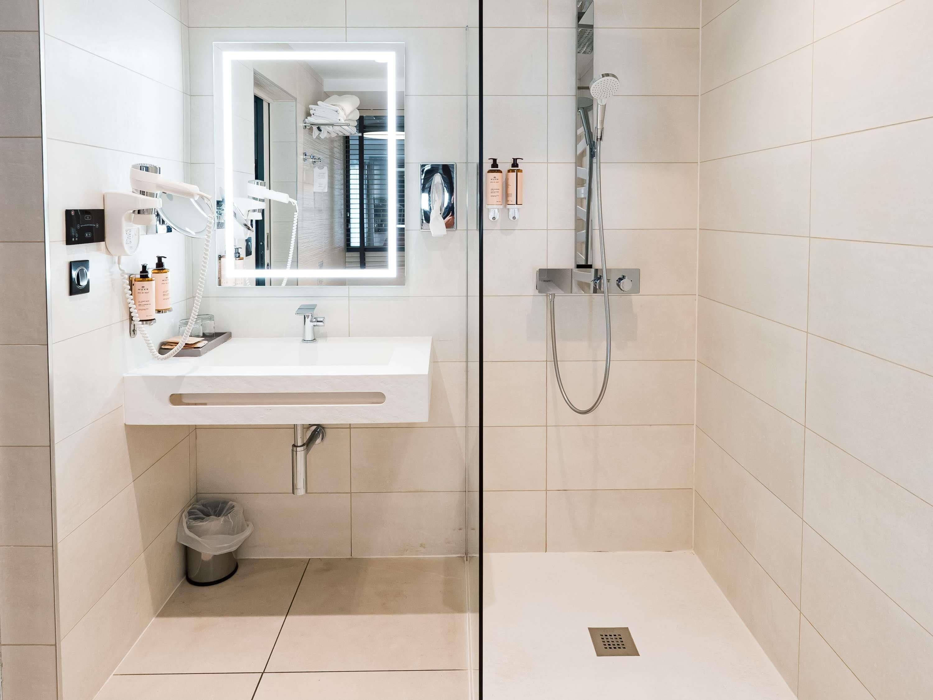 Une salle de bain moderne avec un lavabo blanc, un miroir et une douche.