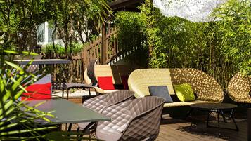 An outdoor seating area with a wicker sofa, cushioned chairs, and a table.