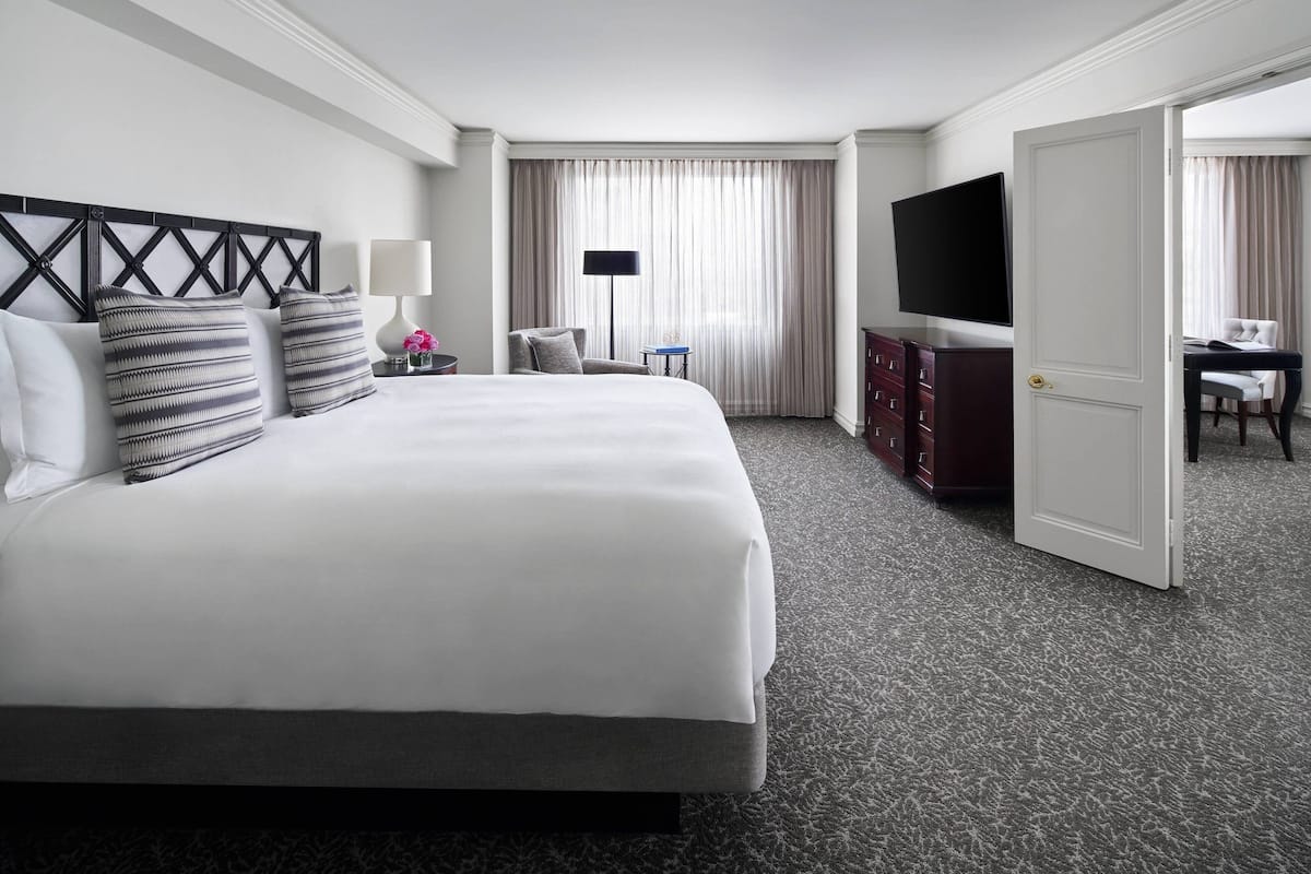 Una habitación de hotel con una cama grande, televisión, escritorio y armario.