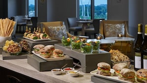 A buffet setup with various food items and a bottle of wine.