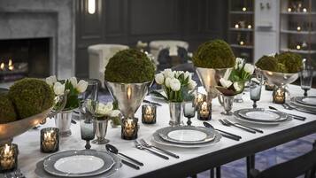 Una mesa de comedor dispuesta con platos blancos, cubiertos y adornos de musgo.