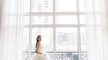 A spacious room with large windows, a chandelier, and a view of buildings outside.