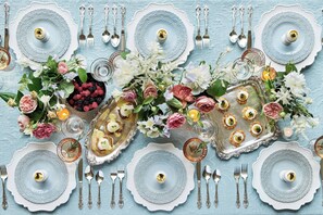 A table set with multiple plates, silverware, and decorative flowers.