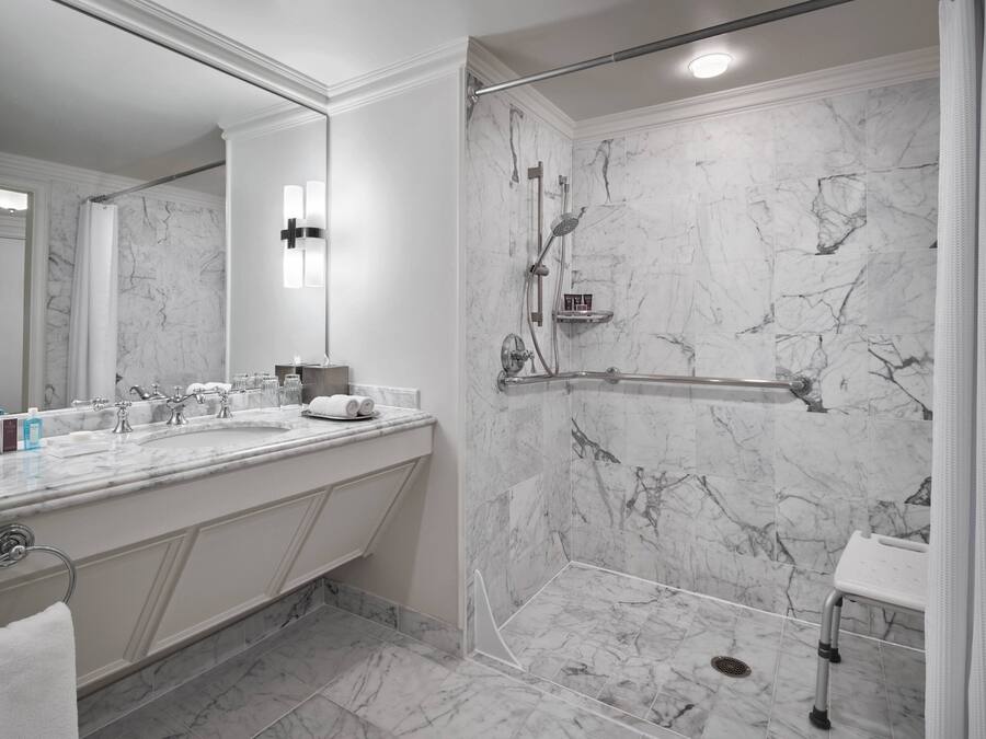 Et moderne badeværelse med kommode i marmor, en brusekabine og et glasafskærmet toilet.