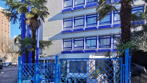 A multi-story building with blue-framed windows and a gated entrance. - La Posada de El Chaflán (Madrid)