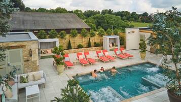 A swimming pool area with lounge chairs and a small garden.