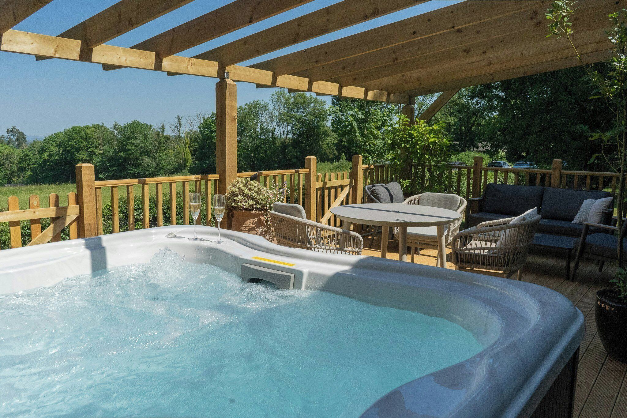 A hot tub with wooden deck seating and a pergola overhead.