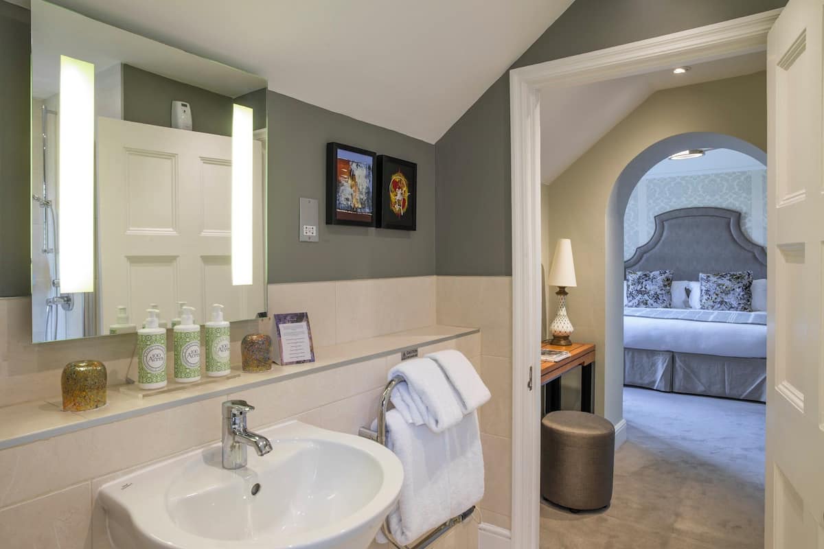A modern bathroom with a large sink, a mirror, and toiletries on the counter.