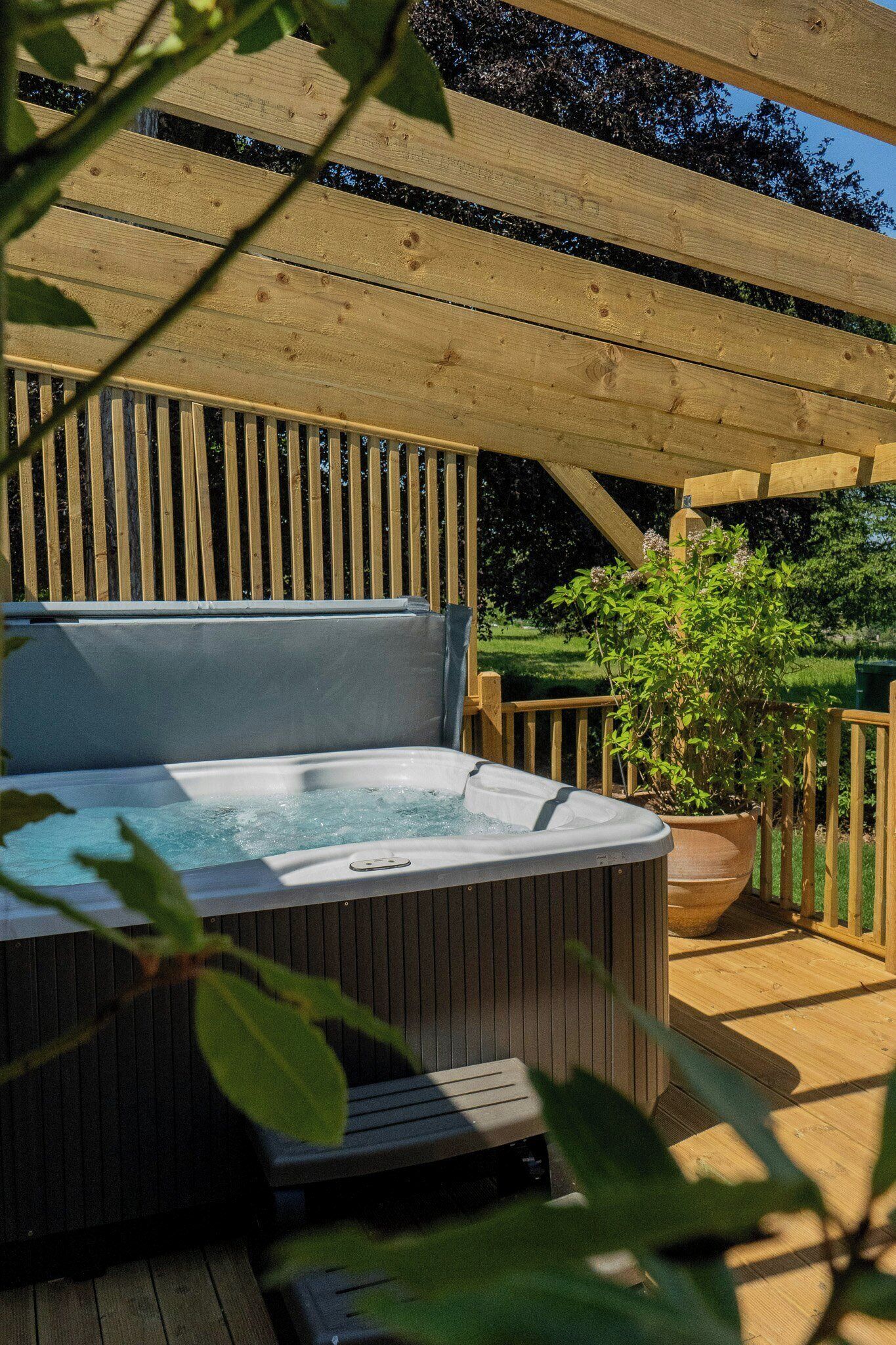 Et spabad med en træterrasse og et pergolaoverhang.
