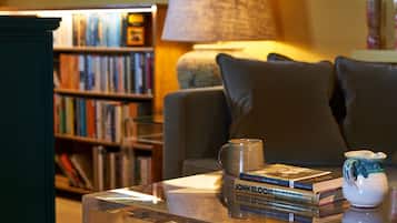Una sala de estar con una estantería, una mesa de centro con libros, una lámpara y un sofá.